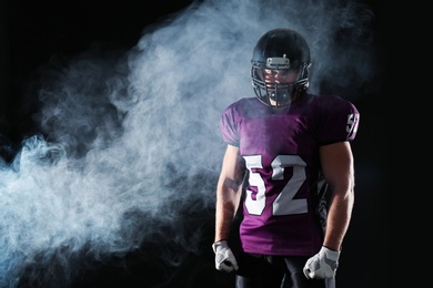 Photo of American football player wearing uniform on dark background. Space for text