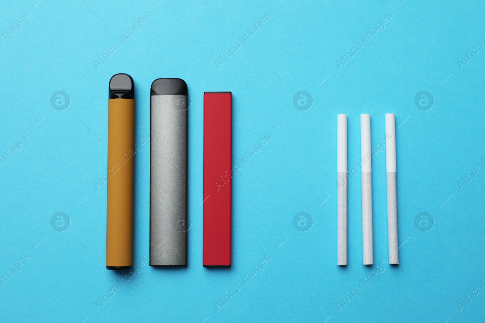 Photo of Electronic and regular cigarettes on light blue background, flat lay