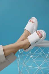 Photo of Woman wearing comfortable rubber slippers on light blue background, closeup