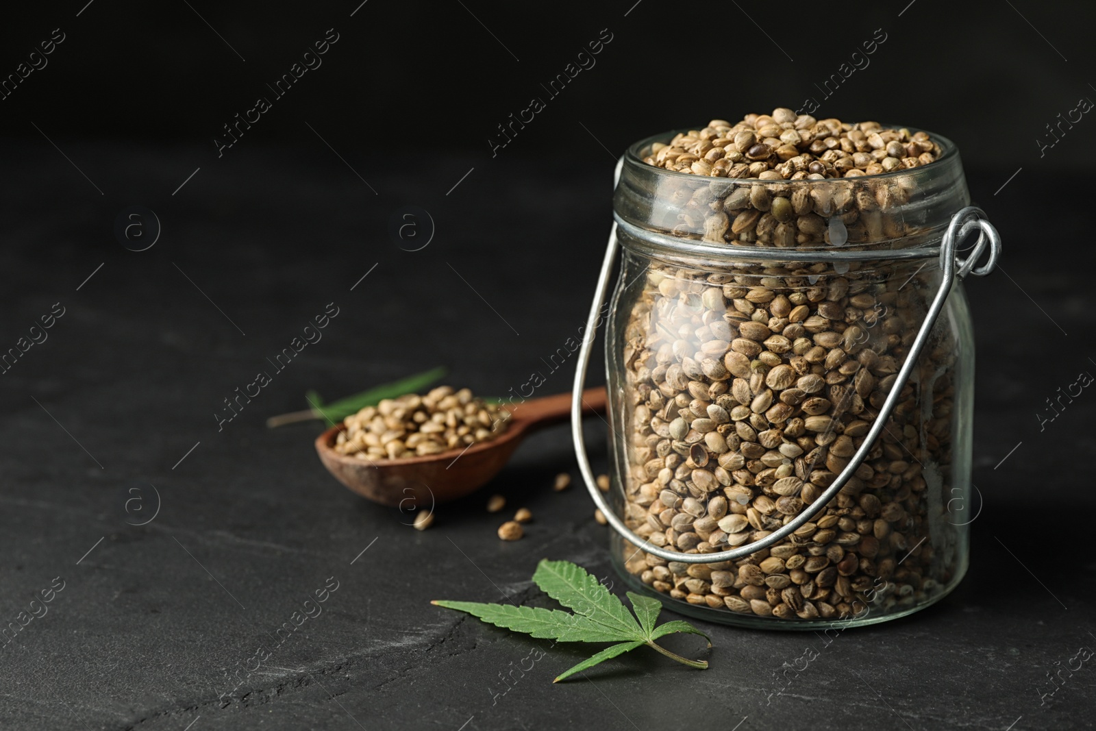 Photo of Organic hemp seeds and leaf on black table