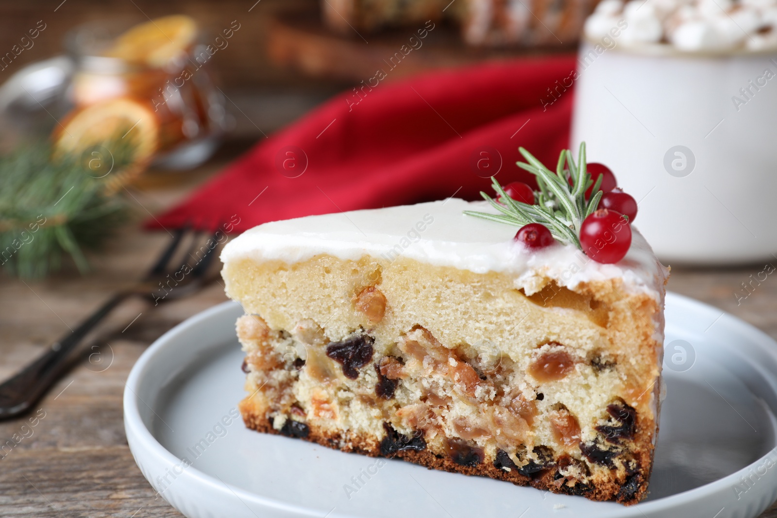 Photo of Slice of traditional Christmas cake decorated with rosemary and cranberries on table, closeup