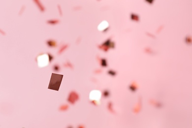 Shiny silver confetti falling down on pink background