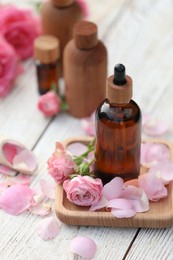 Photo of Rose essential oil and flowers on white wooden table