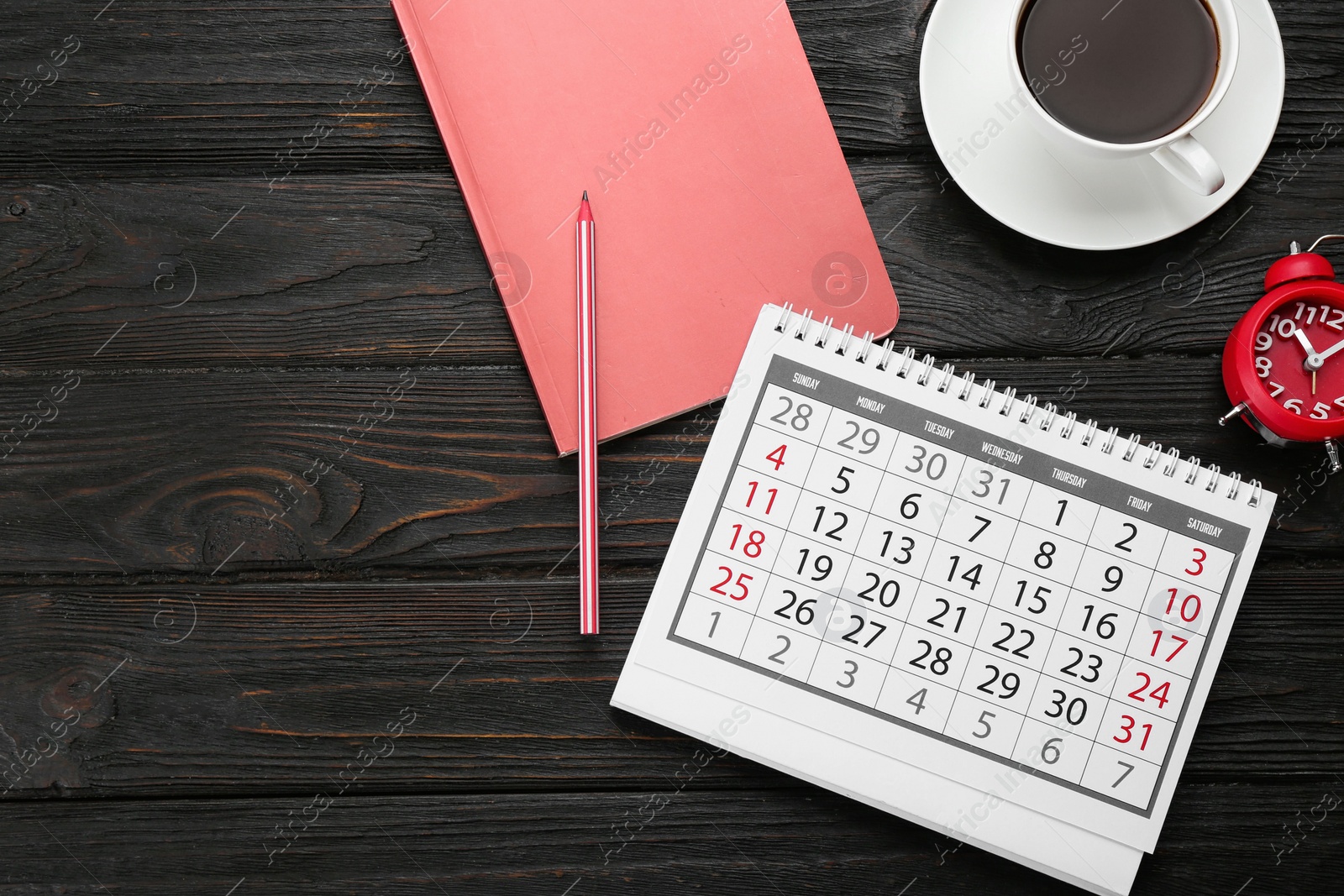 Photo of Flat lay composition with calendar and cup of coffee on black wooden table