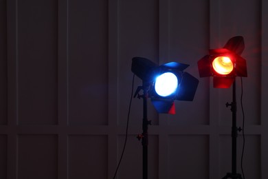 Bright red and blue spotlights near wall in dark room, space for text