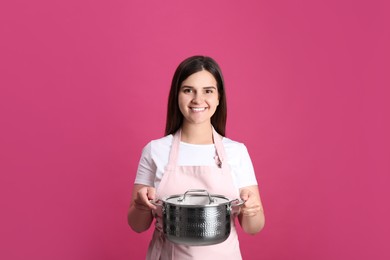 Photo of Happy young woman with cooking pot on pink background