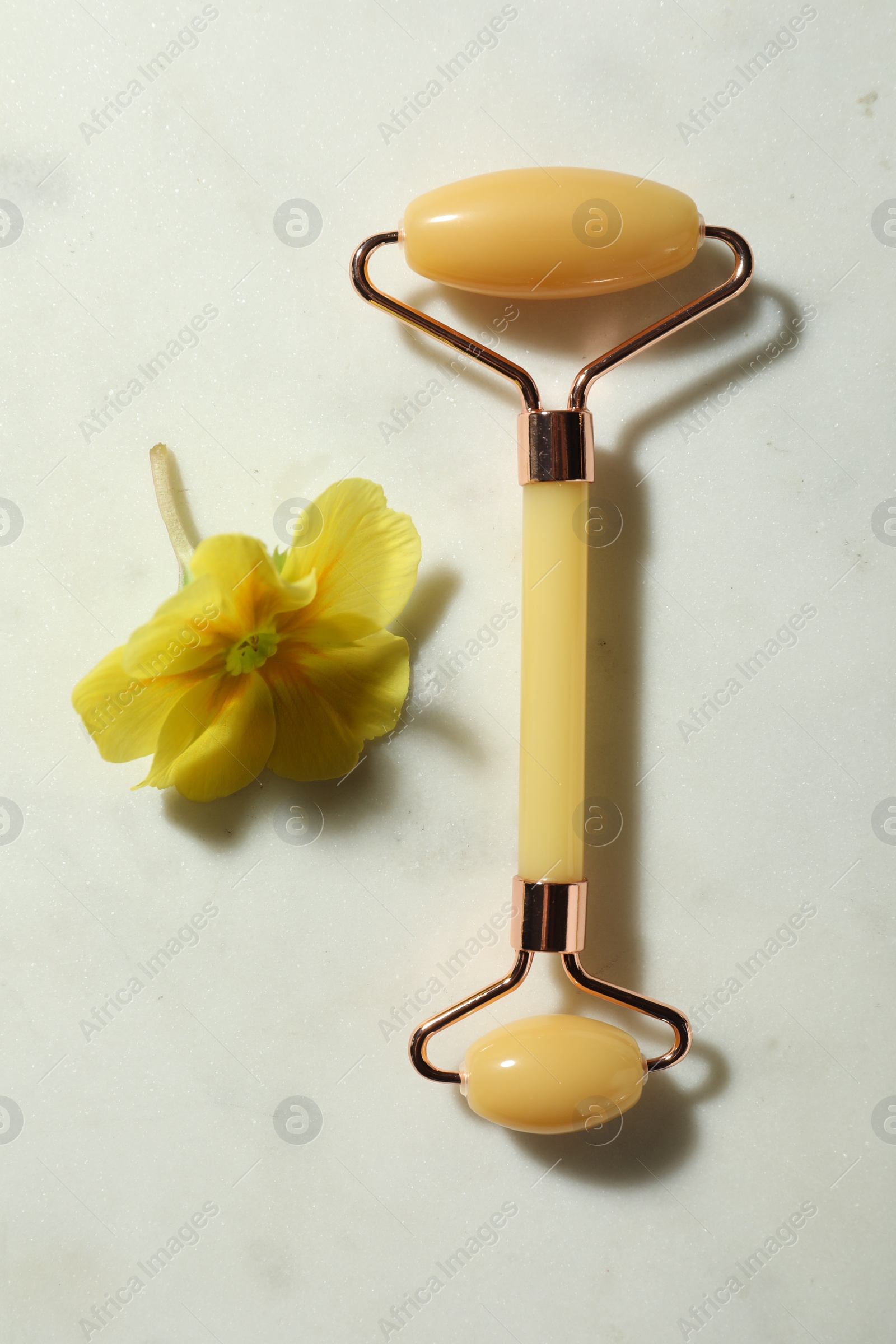 Photo of Natural jade face roller and flower on light background, flat lay