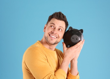 Man with piggy bank on color background