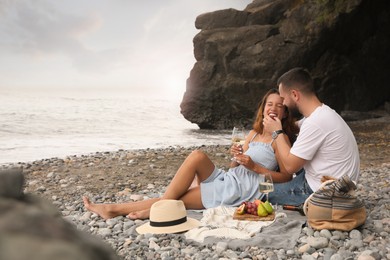 Photo of Happy young couple having picnic on beach near sea. Space for text