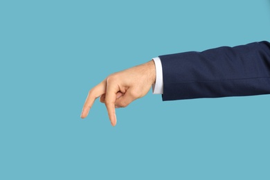 Photo of Businessman imitating walk with hand on light blue background, closeup. Finger gesture