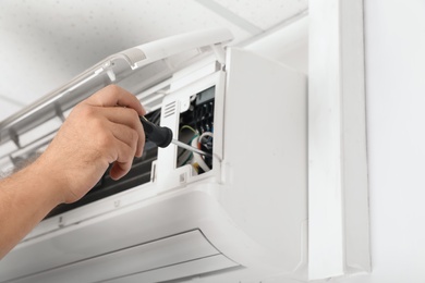 Male technician repairing air conditioner indoors