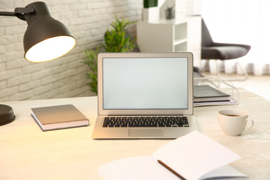 Modern laptop and cup of coffee on white table indoors. Space for design