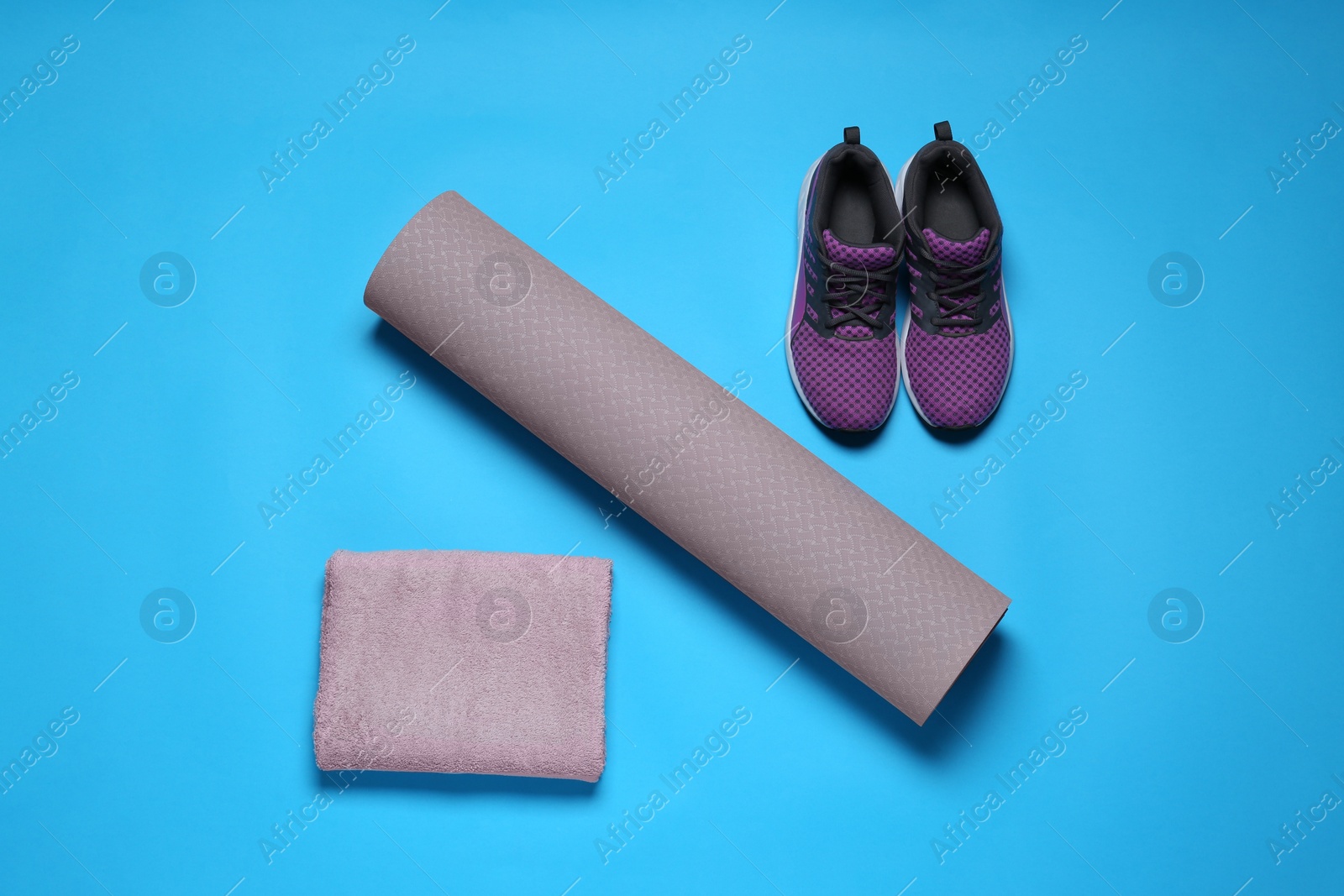 Photo of Exercise mat, towel and shoes on turquoise background, flat lay