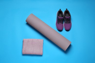 Exercise mat, towel and shoes on turquoise background, flat lay