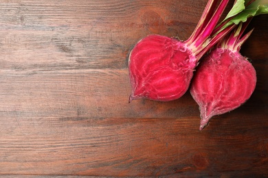 Photo of Halves of raw beet on wooden table, flat lay. Space for text