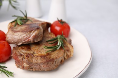 Delicious fried meat with rosemary and tomatoes on white table, closeup