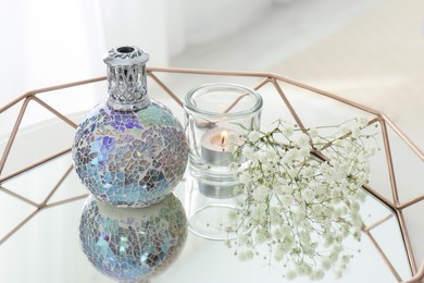 Photo of Stylish catalytic lamp with burning candle and gypsophila on tray in room. Cozy interior