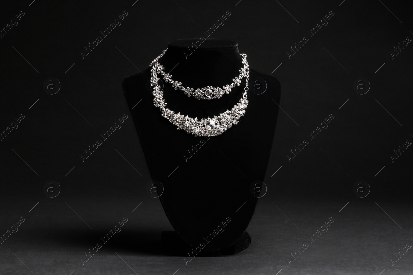 Photo of Elegant necklaces on stand against black background. Luxury jewelry