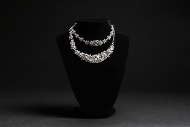 Photo of Elegant necklaces on stand against black background. Luxury jewelry