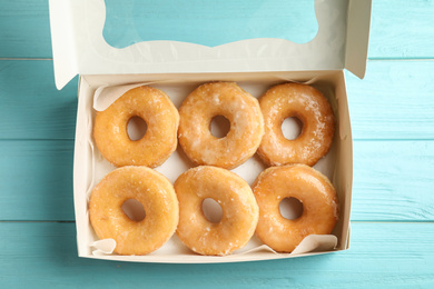 Delicious donuts on light blue table, top view