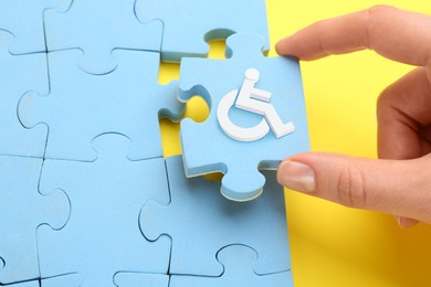Image of Inclusion concept. Woman putting light blue puzzle with international symbol of access together, closeup