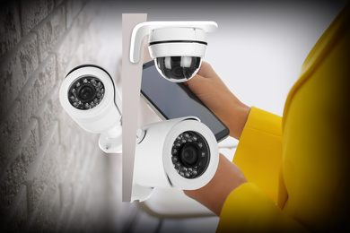 Image of CCTV cameras and woman with smartphone indoors, closeup