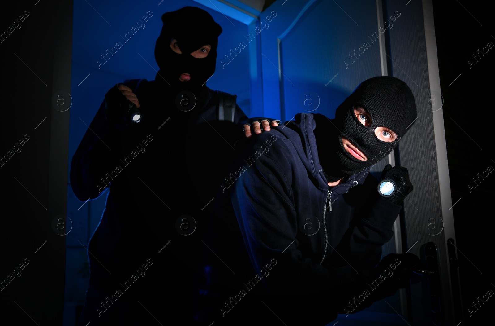 Photo of Thieves with flashlights breaking into house at night