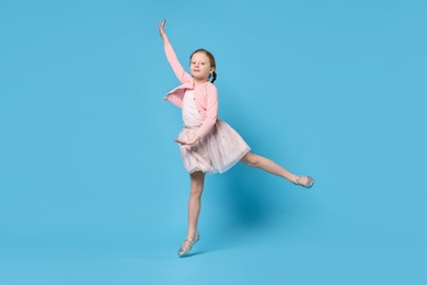 Cute little girl dancing on light blue background