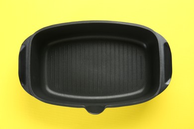 Photo of Black pot on yellow background, top view