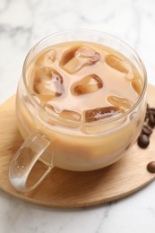 Photo of Refreshing iced coffee with milk in glass cup on white table, closeup