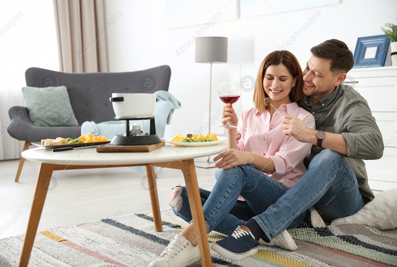 Photo of Happy couple enjoying fondue dinner at home