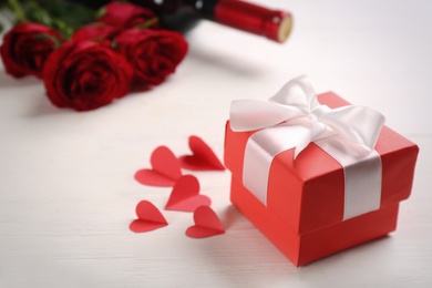 Photo of Beautiful gift box and paper hearts on white wooden table, space for text. Valentine's Day celebration