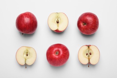 Whole and cut red apples on white background, flat lay