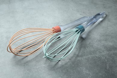 Two whisks on gray table, closeup. Kitchen tool