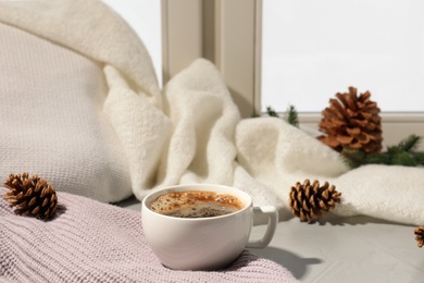 Cup of coffee on windowsill indoors, space for text. Winter drink