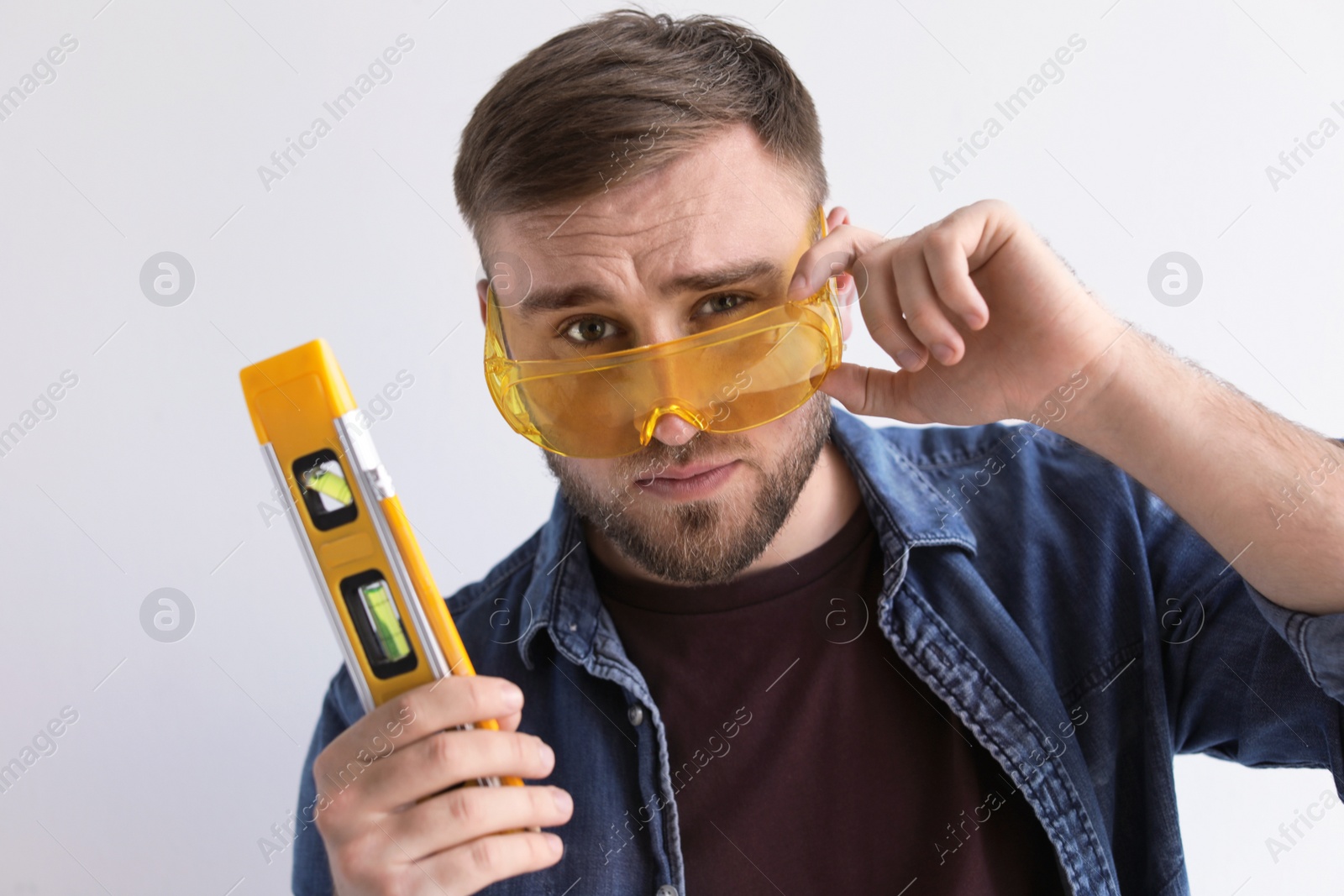 Photo of Young working man with construction level on white background