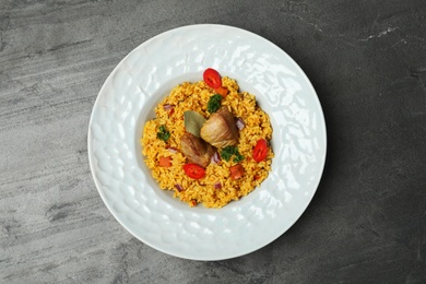 Photo of Plate with rice pilaf and meat on grey background, top view