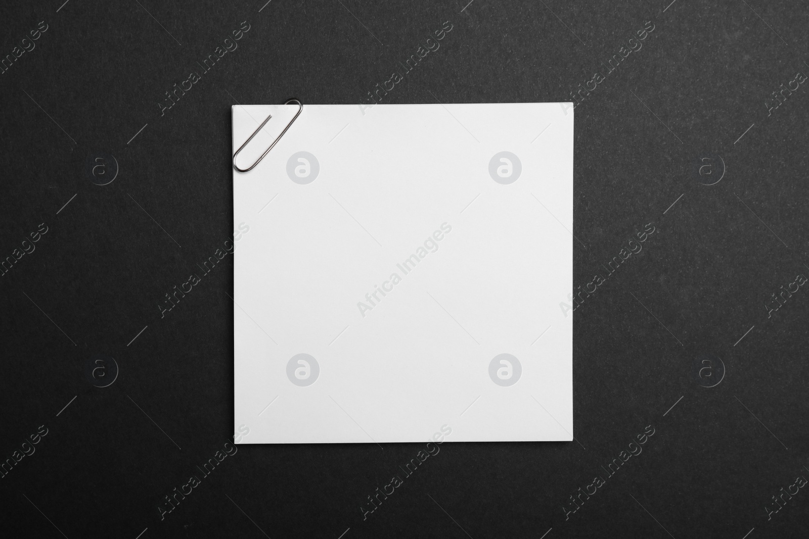 Photo of Sheet of paper with clip on black background, top view