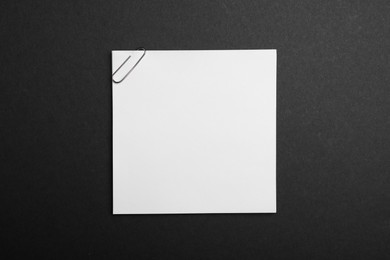 Photo of Sheet of paper with clip on black background, top view