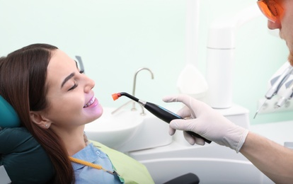 Photo of Professional dentist working with patient in modern clinic. Teeth whitening