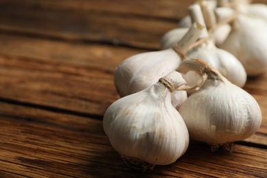 Photo of Fresh organic garlic on wooden table, closeup. Space for text
