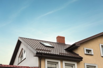Photo of Beautiful house with brown roof against blue sky, low angle view