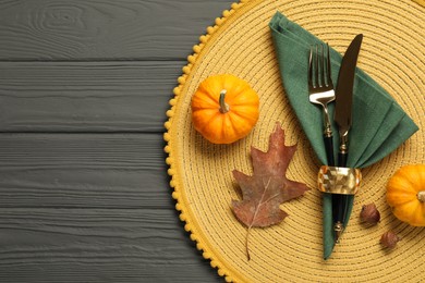 Photo of Cutlery, napkin and pumpkins on gray wooden background, flat lay with space for text. Table setting