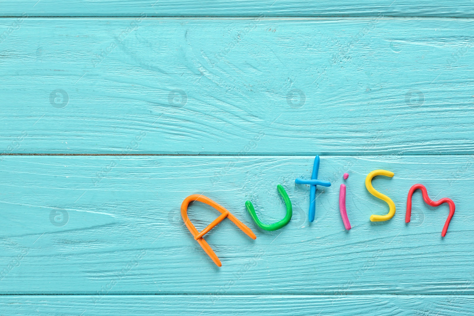 Photo of Word "Autism" made of plasticine on color wooden background