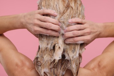 Woman washing hair on pink background, back view