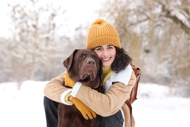 Photo of Woman with adorable Labrador Retriever dog in snowy park