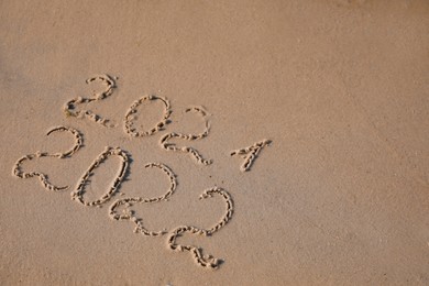 2021 and 2022 written on sand at beach, above view. New Year celebration