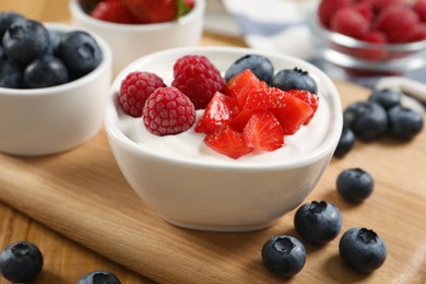 Photo of Delicious yogurt served with berries on wooden table, closeup