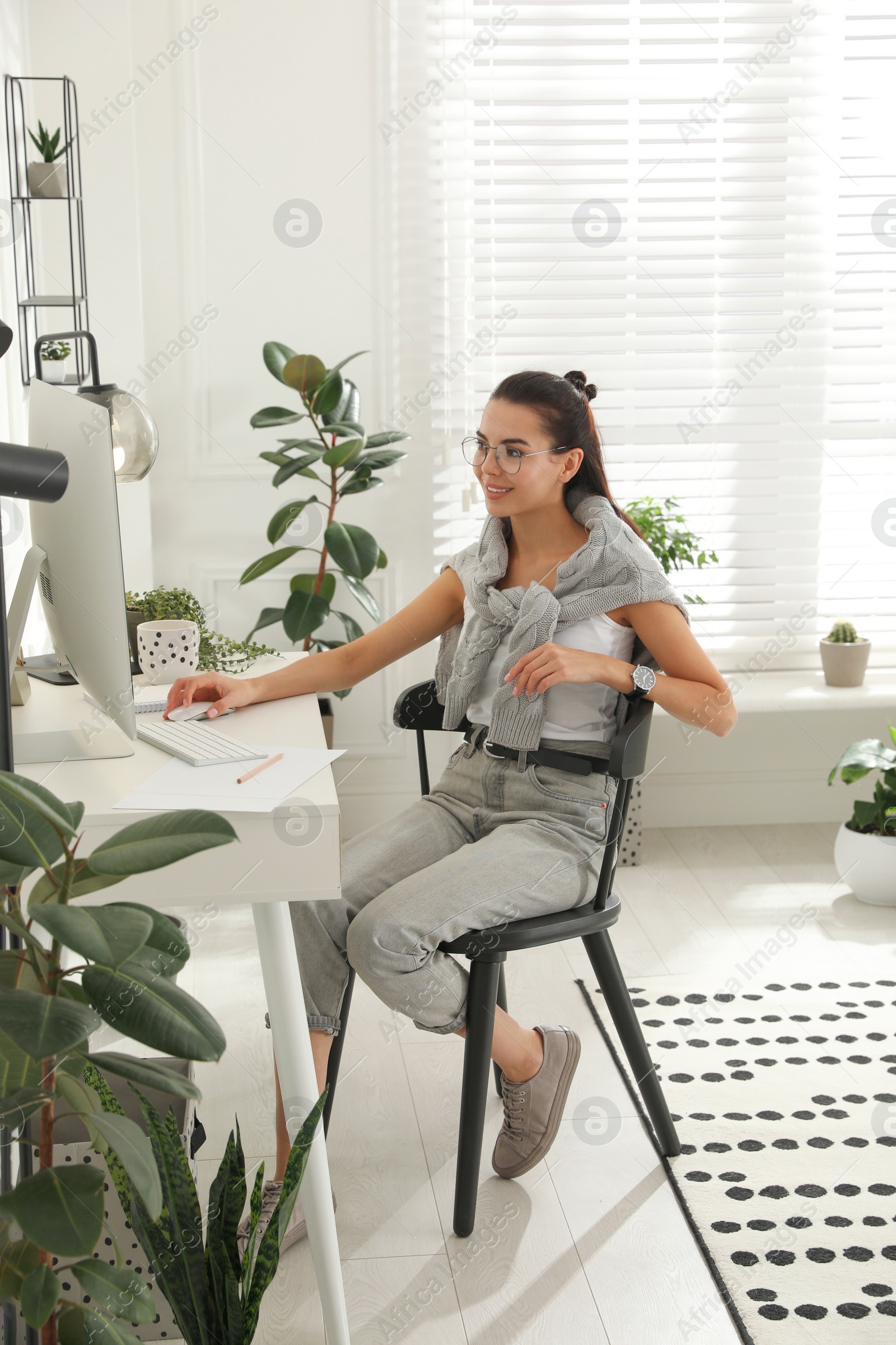 Photo of Young woman working at table in light room. Home office