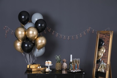 Photo of Party treats and items on table in room decorated with balloons